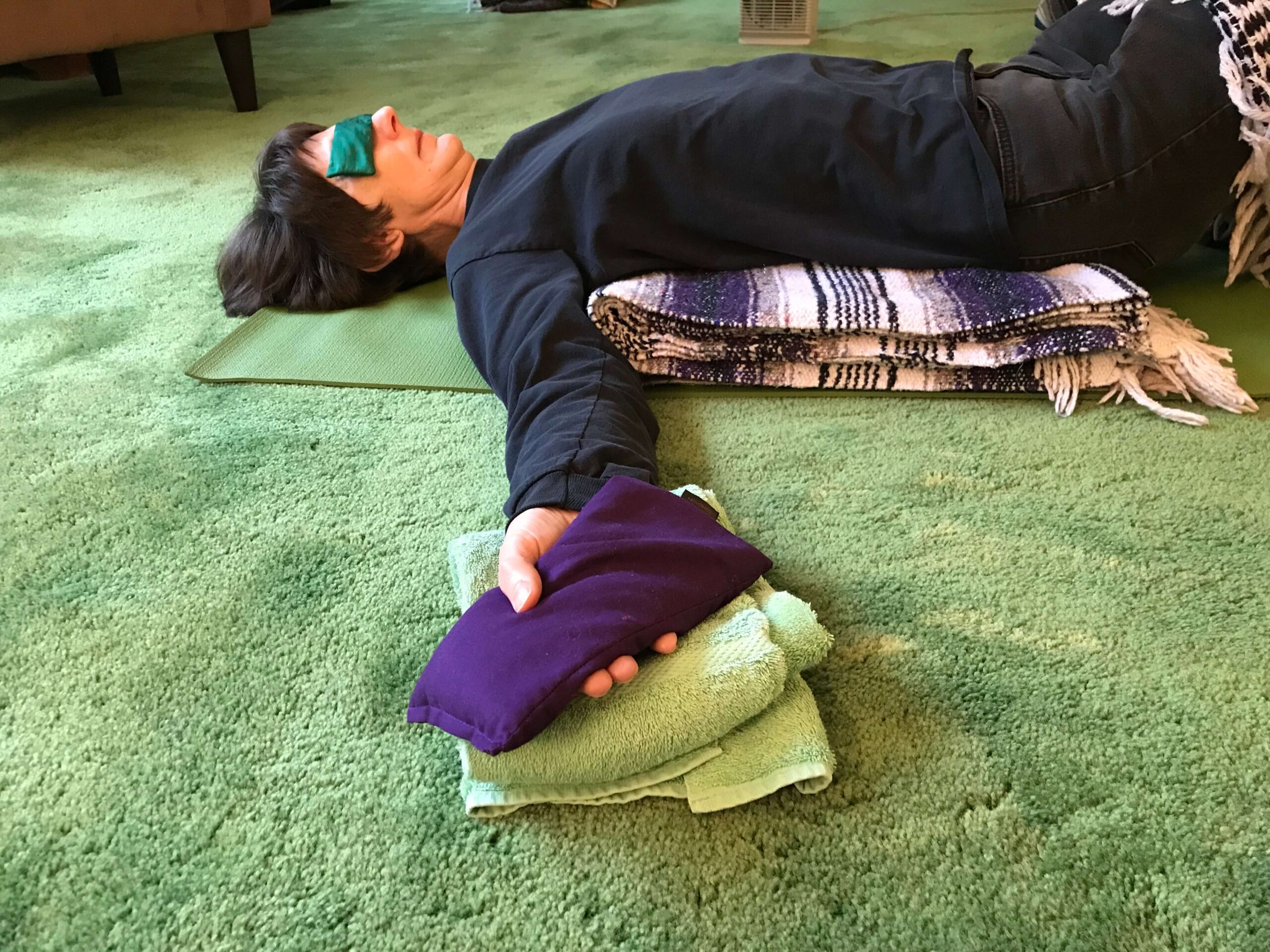 woman laying on the floor doing restorative yoga